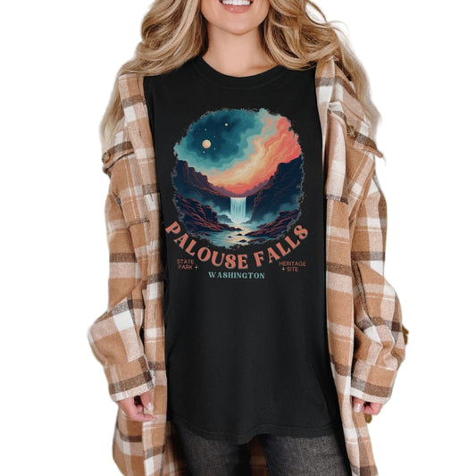 A woman standing with a flannel shirt and a black t-shirt with 'PALOUSE FALLS, WASHINGTON' printed on it.